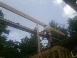 Carpenter setting a ridge beam over a new addition frame — Ice Dam Removal by Roofing Brothers in Lucile