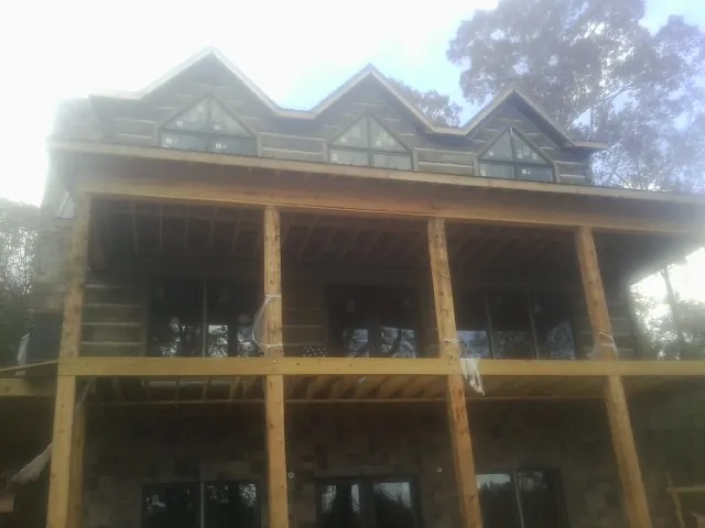 Dormers and porch framing on a large log home under construction — Roof Coating work by our crew in Lucile