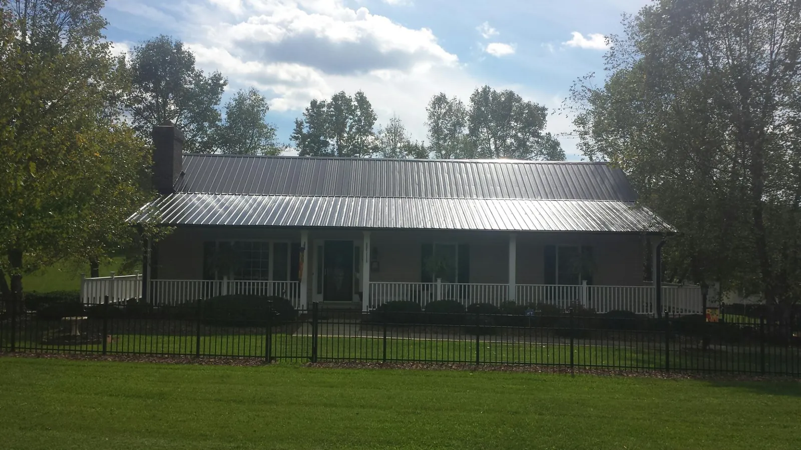 Gray metal roof on a brick ranch with a full width front porch — Gutter Guard Installation work by our crew in Lucile