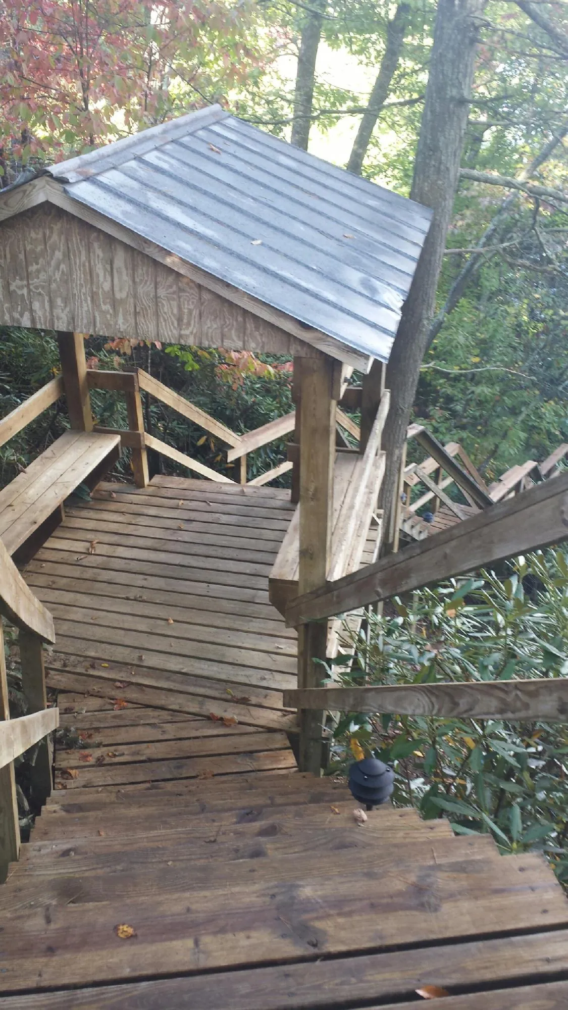 Metal roofed shelter over wooden steps on a wooded walkway — Skylight Repair & Installation work by our crew in Lucile
