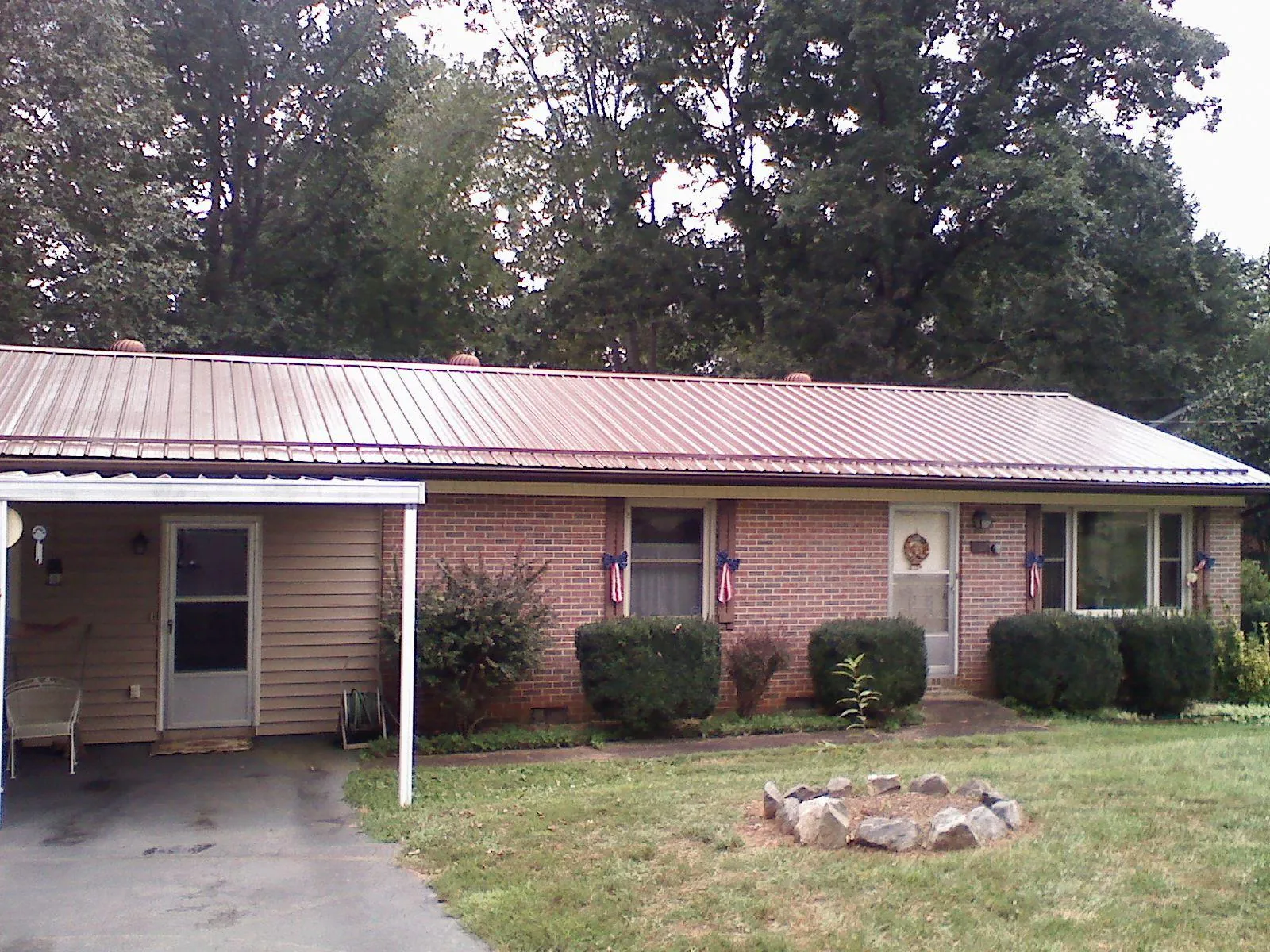 Bronze metal roof and carport on a brick ranch home — Roof Repair work by our crew in Lucile