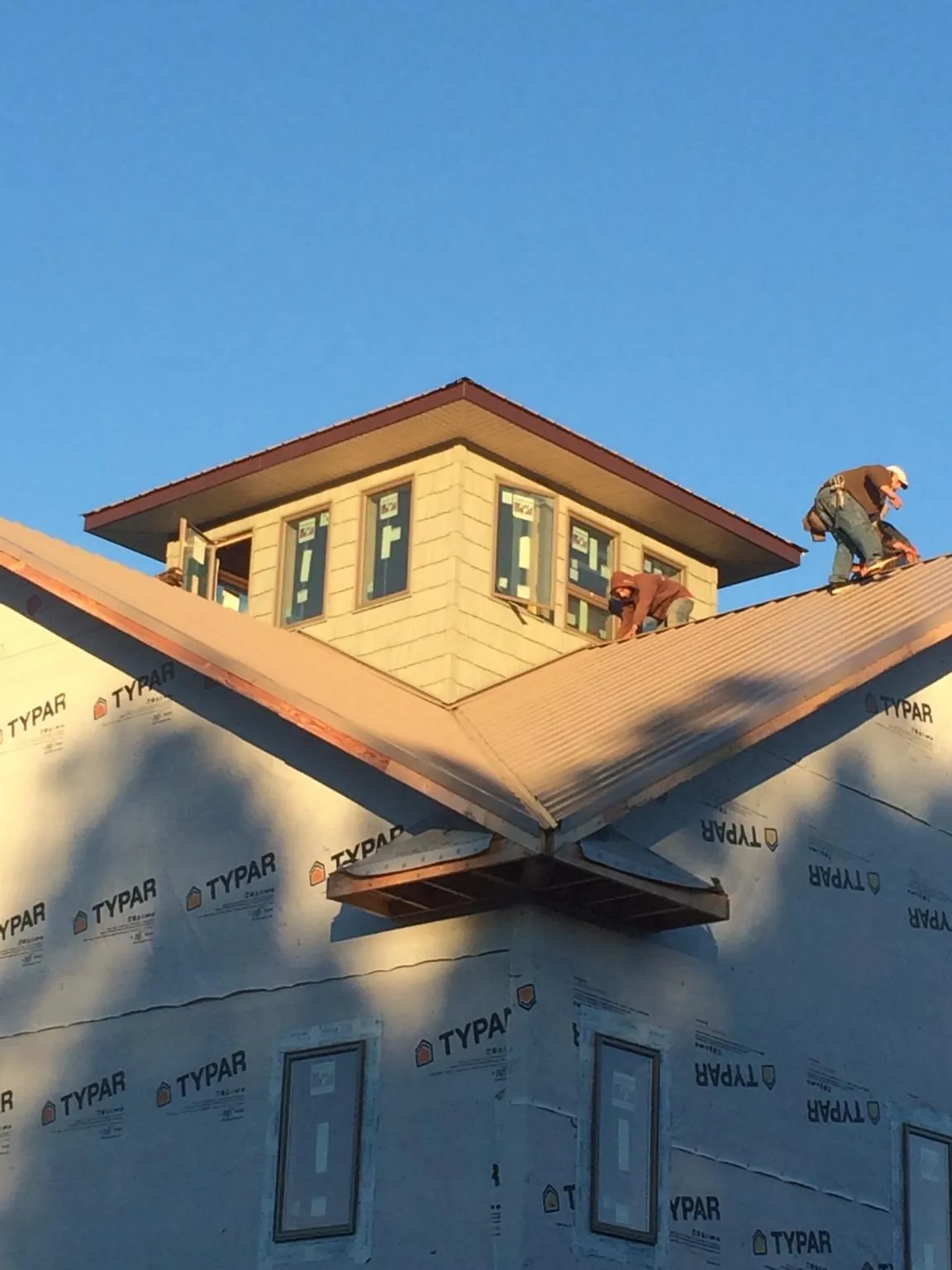 Roofers working around a rooftop cupola on a new metal roof at sunset — Roof Waterproofing in Lucile by Roofing Brothers